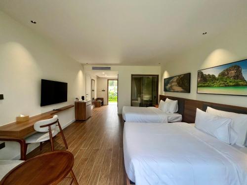 a hotel room with two beds and a flat screen tv at The Vista Beach Resort Phan Thiết in Phan Thiet