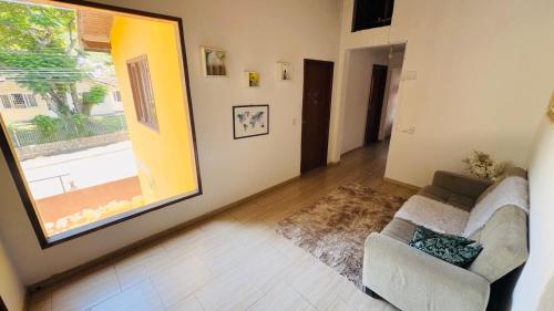 a living room with a couch and a large window at Hostel Ribeirão do Sol in Florianópolis