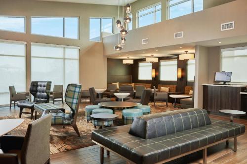 a waiting room with tables and chairs and windows at Residence Inn Sacramento Davis in Davis
