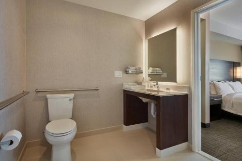 a bathroom with a toilet and a sink and a bed at Residence Inn Sacramento Davis in Davis