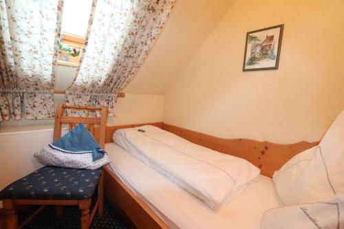a small bedroom with a bed and a chair at Hotel Restaurant Freihof in Oberharmersbach
