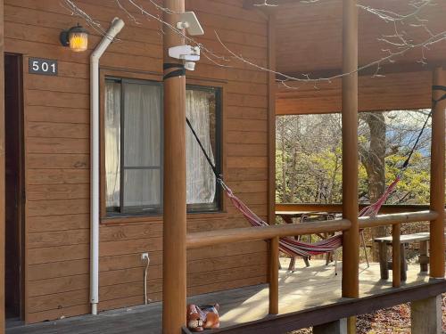 a porch of a log cabin with a hammock at 富士山サクラリゾート in Kai