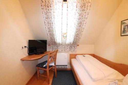 a small room with a bed and a desk with a computer at Hotel Restaurant Freihof in Oberharmersbach