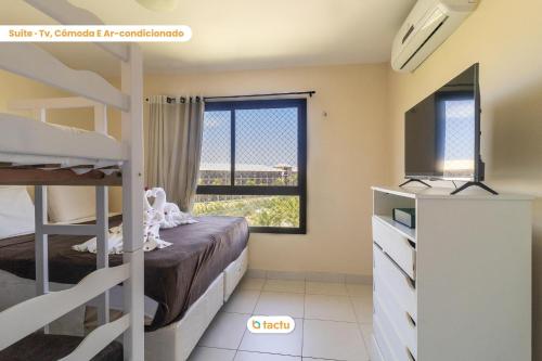 a bedroom with bunk beds and a tv and a window at Apto no VG Sun com acesso exclusivo à praia in Paracumbuca