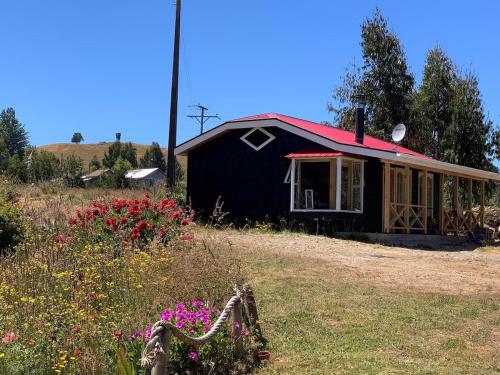 a small black house with a red roof at Balcón del estero isla Puluqui in Calbuco
