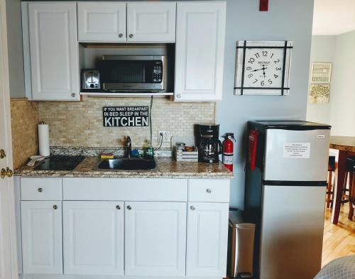 a kitchen with white cabinets and a refrigerator at Lakefront King Studio with Private Porch in Tilton