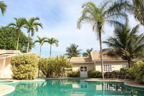a swimming pool in front of a house with palm trees at Paraty Bungalows Bar E Hotel in Paraty
