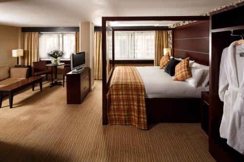 グラスゴーにあるメルキュール グラスゴー シティ ホテルのベッドとリビングルームが備わるホテルルームです。