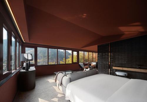 a bedroom with a large white bed and windows at Topscape 仰山 in Qingdao