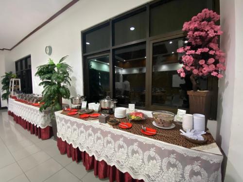 a long table with plates of food and flowers at Graha Widya Bhakti at STIESIA Surabaya in Surabaya