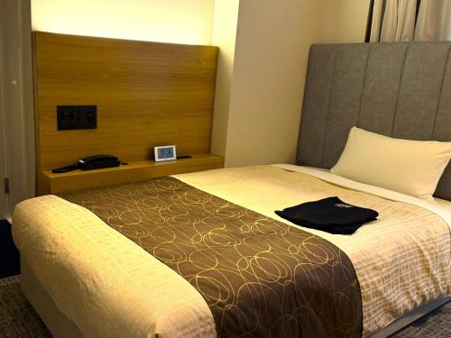 a hotel room with a bed with a black shirt on it at Place Hotel Ascot in Kumamoto