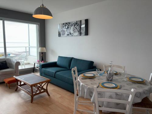 un salon avec une table et un canapé bleu dans l'établissement Appartement moderne 5 pers, balcon, parking, proche plage - FR-1-323-559, à Saint-Hilaire-de-Riez