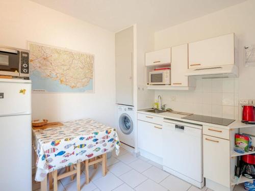 - une cuisine avec des placards blancs, une table et un réfrigérateur dans l'établissement Appartement confortable avec terrasse, proche plages - FR-1-816-1, au Lavandou