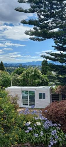 a white house with a tree in front of it at The White Cabin in Tauranga