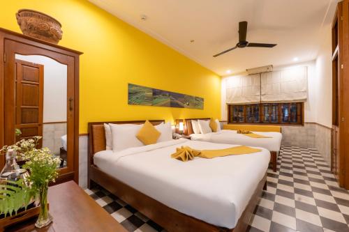 two beds in a room with yellow walls at Thanh Van 1 Hotel in Hoi An