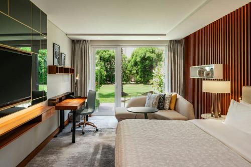 a hotel room with a bed and a desk and a tv at Le Méridien Dubai Hotel & Conference Centre in Dubai