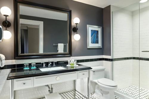 a bathroom with a sink and a toilet and a mirror at Le Meridien Dallas, The Stoneleigh in Dallas