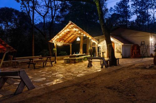 a pavilion with a picnic table and benches at night at Jungle stay by Bilwa Estate in SanivÄrsante