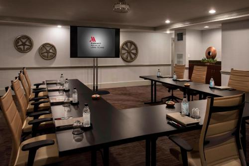 a dining room with tables and chairs and a screen at Marriott Melville Long Island in Melville
