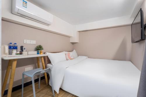 a small white room with a bed and a desk at Shanghai Meego Qingwen Hotel in Shanghai