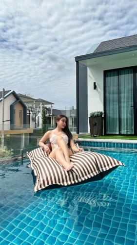 a woman sitting on a pillow next to a swimming pool at Alisto Khaoyai in Wangkata