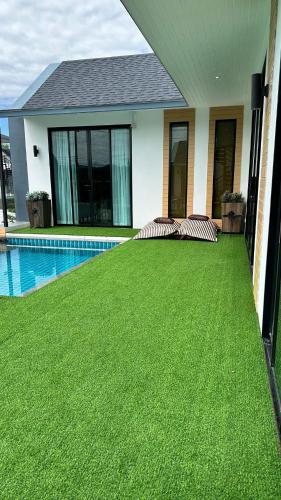 a house with a green lawn next to a swimming pool at Alisto Khaoyai in Wangkata