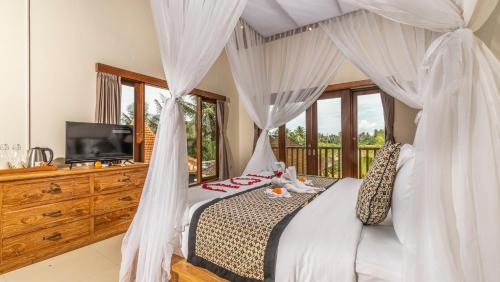 a bedroom with a canopy bed and a television at Tenggala Villa Ubud by Mahaputra in Ubud