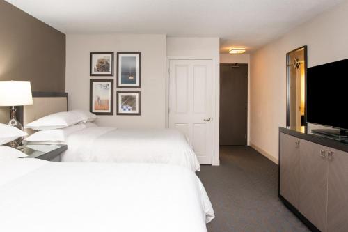 a hotel room with two beds and a flat screen tv at Sheraton Minneapolis West Hotel in Minnetonka