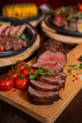 a wooden board with meat and tomatoes on a table at Marriott Hotel Al Forsan, Abu Dhabi in Abu Dhabi