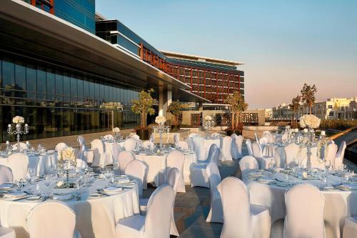 a group of tables with white chairs and tablesearcher at Marriott Hotel Al Forsan, Abu Dhabi in Abu Dhabi