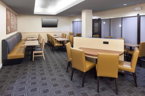 una sala da pranzo con tavoli, sedie e TV di TownePlace Suites Columbia Southeast / Fort Jackson a Columbia