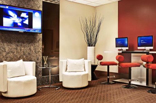 a waiting room with white chairs and a flat screen tv at JW Marriott Los Angeles L.A. LIVE in Los Angeles