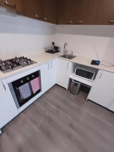 a white kitchen with a stove and a sink at Nice 2 bedroom apartment in Kelmscott