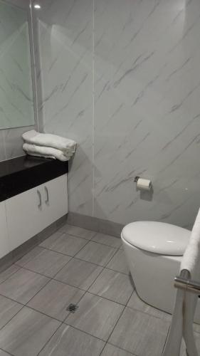 a white bathroom with a toilet and a mirror at Nice 2 bedroom apartment in Kelmscott