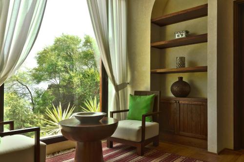 a living room with a window and a chair and a table at Al Bustan Palace, a Ritz-Carlton Hotel in Muscat