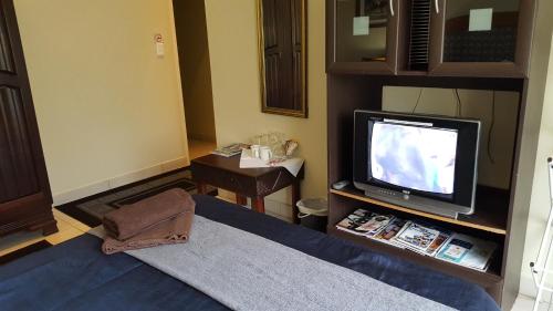 a living room with a tv and a bed at The Homestead Margate - South Africa in Margate