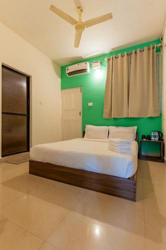 a bedroom with a bed with a green wall at Woodpegger By The Beach, Mandrem in Mandrem