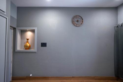 a white wall with a clock and a vase on it at The Lavish Affair in Bhuj