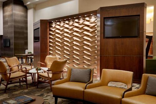 a waiting room with chairs and a flat screen tv at Marriott Hartford/Windsor Airport in Windsor
