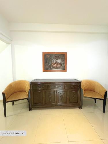 a wooden cabinet and two chairs in a room at 5 Bedroom House Near Sunway Lagoon in Petaling Jaya