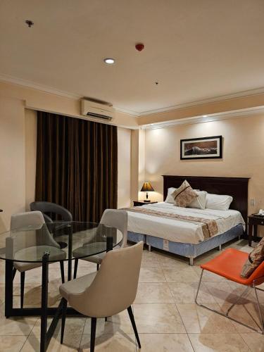 a bedroom with a bed and a glass table and chairs at Valentino's Hotel in Angeles