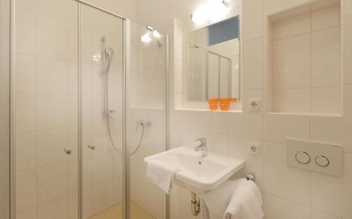 a white bathroom with a sink and a shower at Kraftquelle Schlossblick in Angerberg