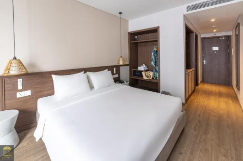 a bedroom with a large white bed and a hallway at Resort Mandala's By Cozy Apec in Mui Ne