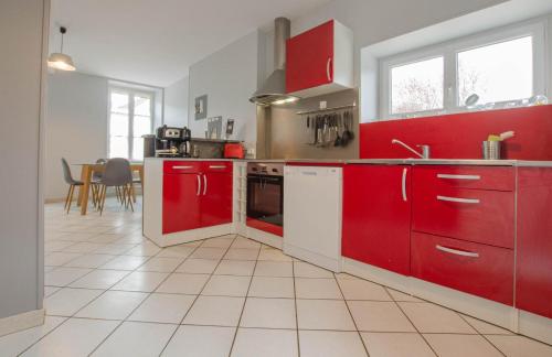a kitchen with red cabinets and a white tile floor at Le gite de la sarce in Beauvoir-sur-Sarce