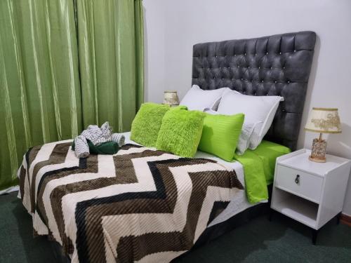Un dormitorio con una cama con almohadas verdes y blancas. en The Leafy Haven- A feel of home!, en Harare
