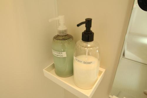two bottles of soap are sitting on a shelf in a bathroom at Casa上熊本 1 in Kumamoto