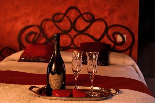 a bottle of wine and two glasses on a bed at Affittacamere Valnascosta in Faedis