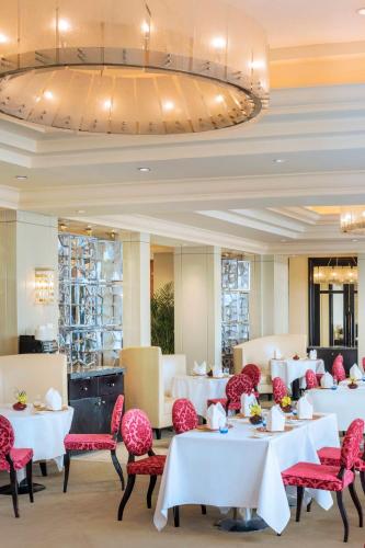 a dining room with white tables and red chairs at The St. Regis Beijing in Beijing