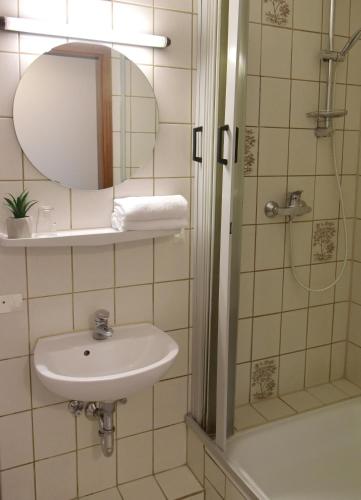 a bathroom with a sink and a shower with a mirror at Pension Haus Bambi in Mölln