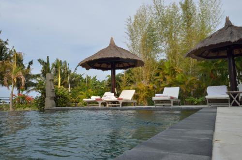 una piscina en un complejo con sillas y sombrillas en Villa Danison, en Umeanyar